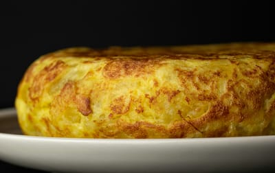 Close-up of a Spanish tortilla on a white plate, photographed by blackieshoot on Unsplash. 